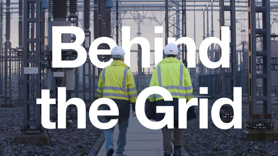 Two people wearing helmets and high-vis jackets walking through an electricity substation with the words 'Behind the Grid' across the image
