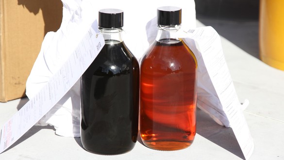 Two glass bottles, one with dirty and one with clean oil