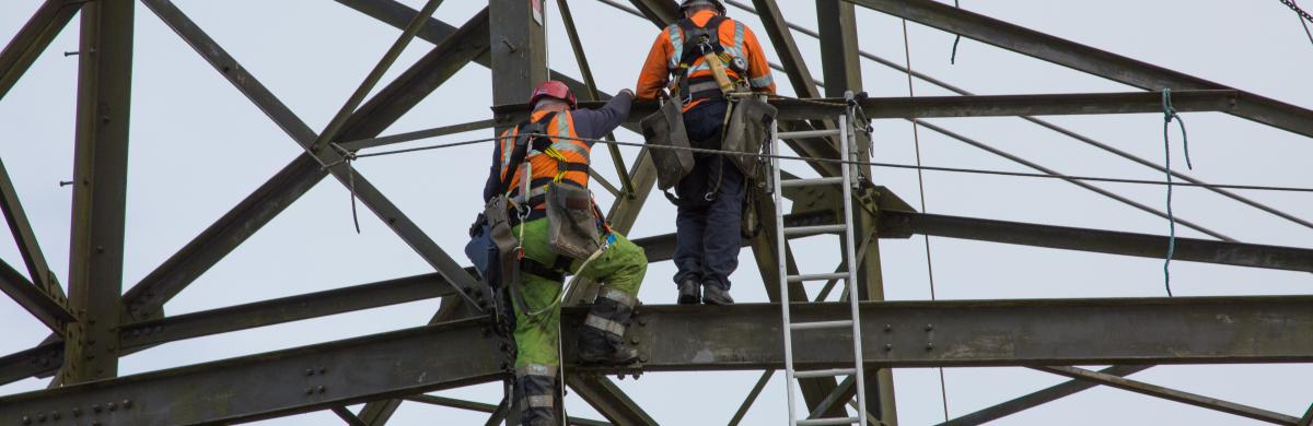 Two National Grid workers climbing onto a steel framework - Swansea to Pembroke