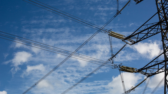 A partial view of a Deeside electricity pylon with a blue and cloudy sky in the background