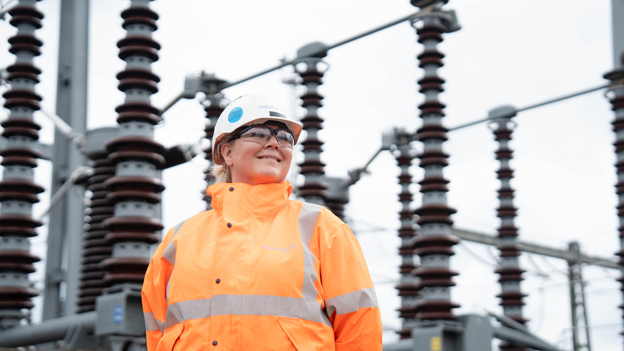 National Grid woman engineer wearing hard hat and orange high-vis jacket at Burwell substation