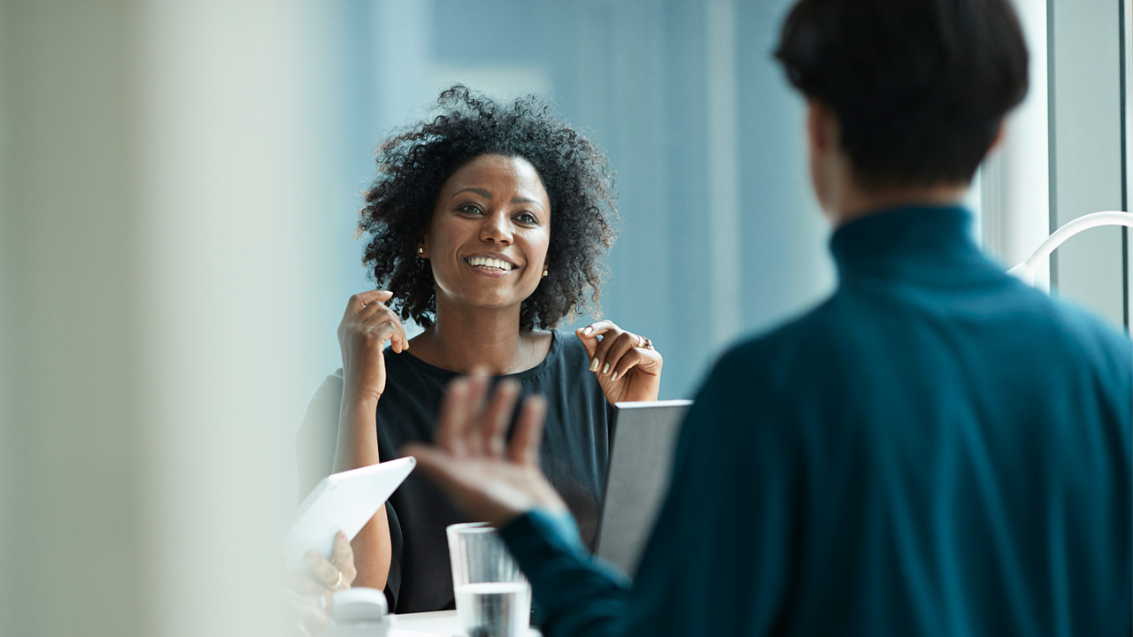 Two people talking to each other across a desk in an office