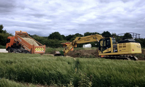 Digger and lorry in green field