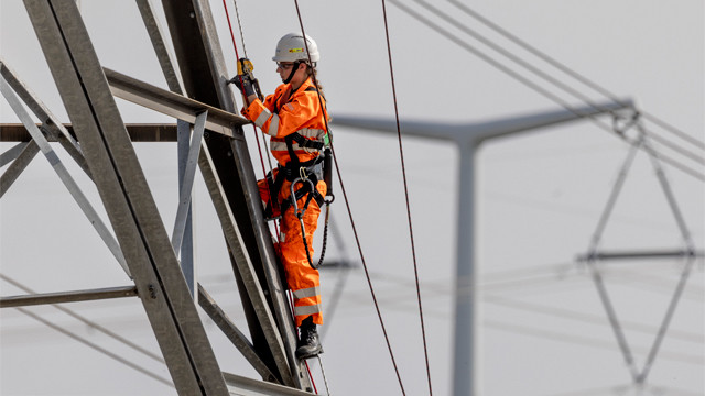 Woman engineer wearing full PPE and harness climbing an electricity pylon