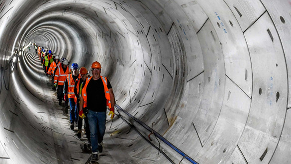Line of people wearing hard hats and high-vis jackets walking through concrete tunnel - used for the National Grid story 'Celebrating the completion of the Humber Tunnel'