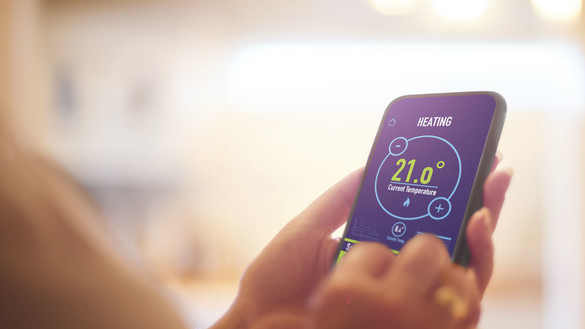 Hands holding a smart device showing heating and current temperature information - used for the National Grid story 'The future of home heating in a net zero UK'