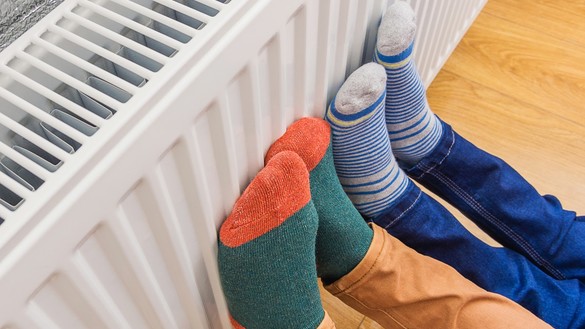 Two pairs of feet in colourful socks held against a radiator