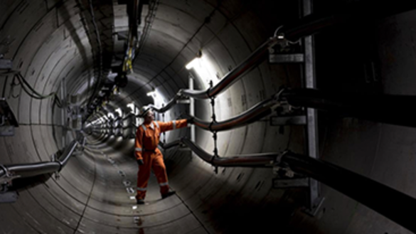 Engineer wearing orange overalls and a hard hat standing inside National Grid's London Power Tunnel