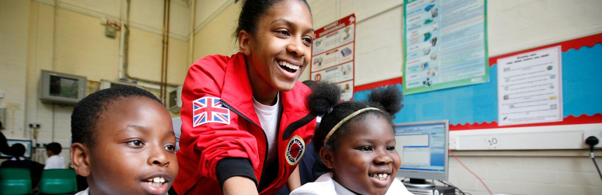 Three young people looking at something excitedly with a classroom setting in the background - Organisations we work with