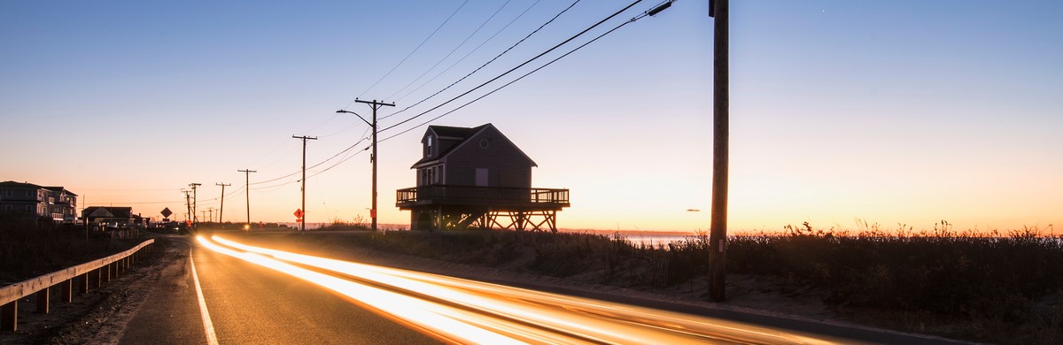 Blurred headlight of car on road by the shore at dawn