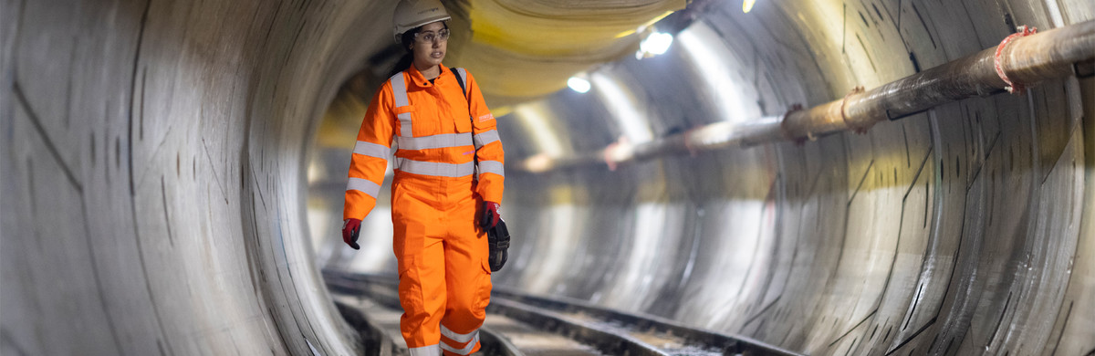 An engineer wearing hard hat and PPE walking inside London Power Tunnels