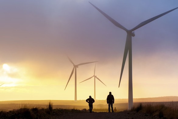 Two people standing under a wind turbine at sunset for National Grid article