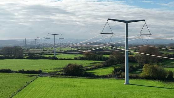 T-pylons and overhead electricity lines across green fields